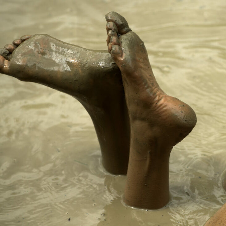 Dirty heels and feet. Legs butt in mud bath. Woman in the mud bath. Spa procedure and body care. Enjoying mud
